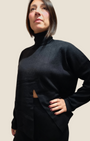 Modella indossa completo nero Madison Shop in maglia con dolcevita e apertura frontale, stile minimalista casual-chic