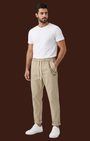 Madison Shop model wearing beige relaxed fit chino pants with elastic waist, drawstring, and chain detail.