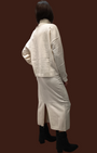 Modella di spalle indossa completo Madison Shop color panna con maglia a collo alto e gonna midi in maglia