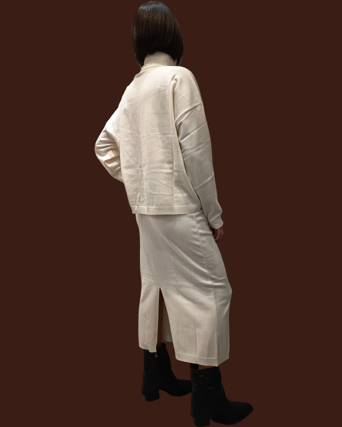 Modella di spalle indossa completo Madison Shop color panna con maglia a collo alto e gonna midi in maglia