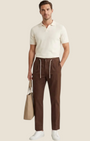 Madison Shop brown cotton chino trousers with front pleats and drawstring waist worn by a man with a beige tote bag